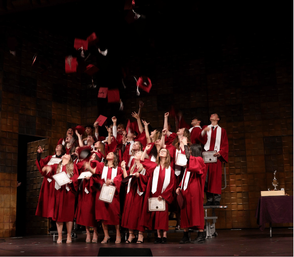 Graduation Class in gowns throwing hats at Fraser Academy in Vancouver, BC