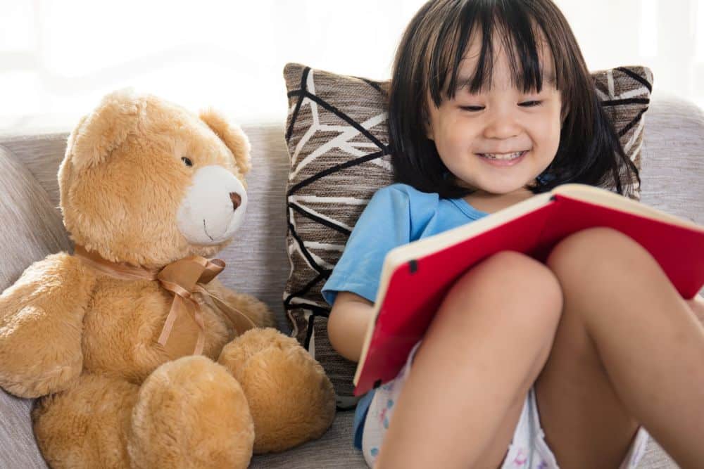 girl reading to stuffy