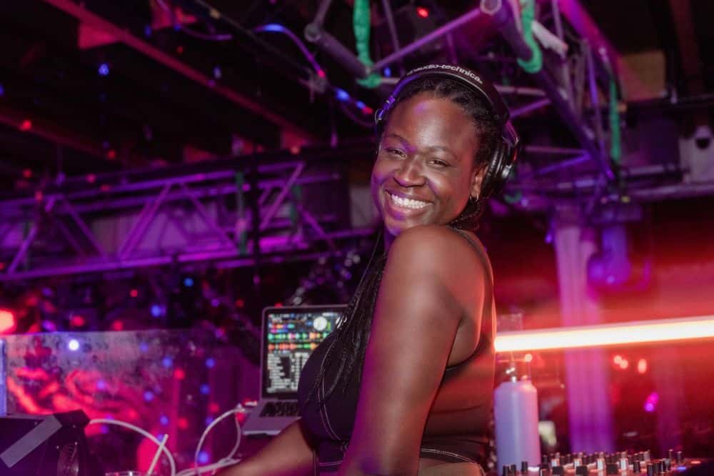 Woman with headphones on "dj"ing at an event.
