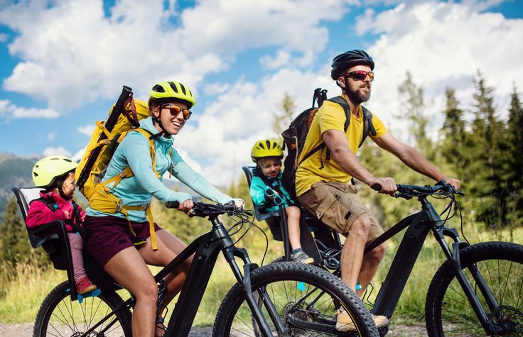Mom and dad on a bike ride with kids in carriers behind them.