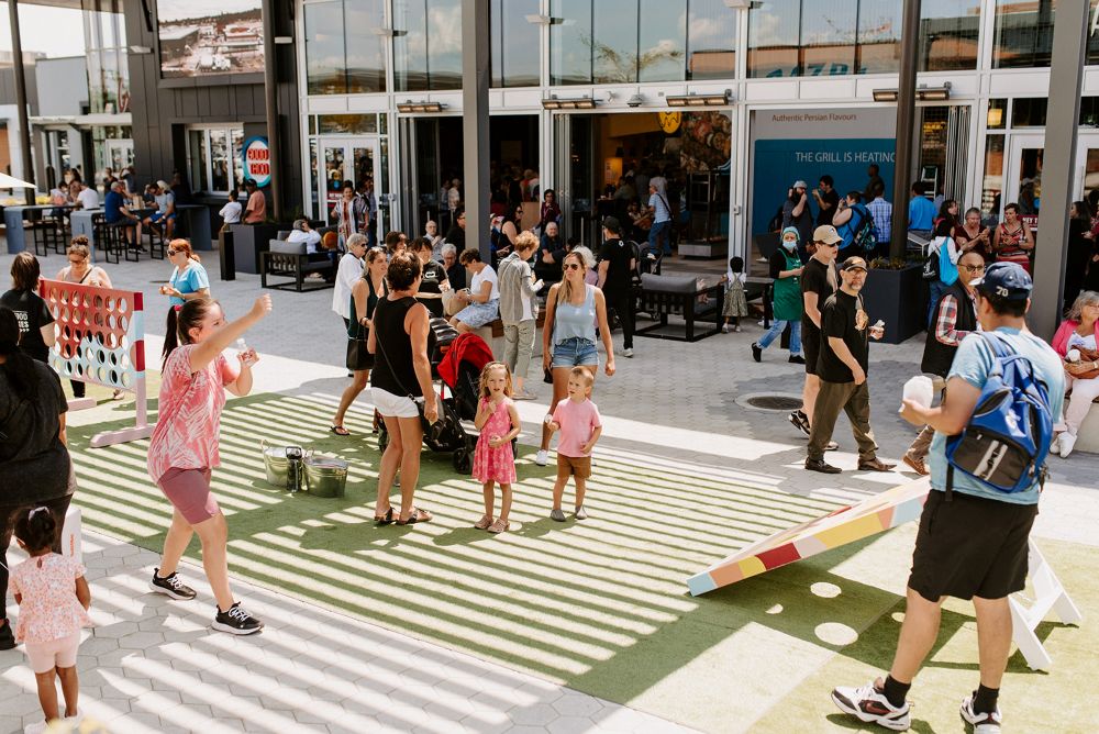 Outdoor event with children watching a woman blow bubbles, and others walking by to see the event.