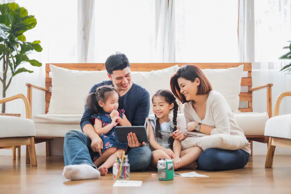 Digital era-Happy Asian family using tablet, laptop for playing game watching movies, relaxing at home for lifestyle concept