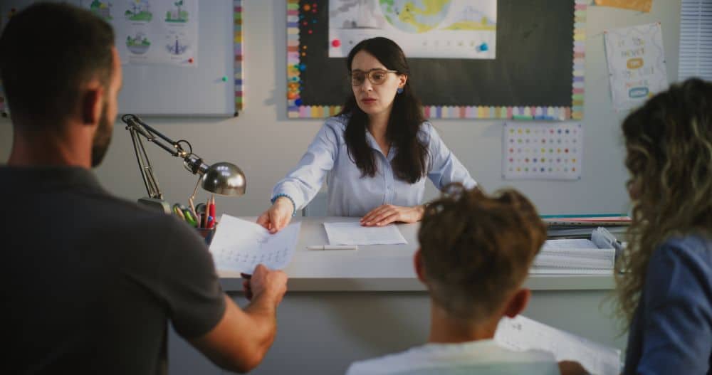 Parents and a neurodivergent child with a teacher looking at a test.