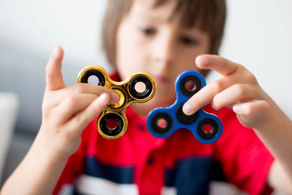 A child holding two fidget spinners.