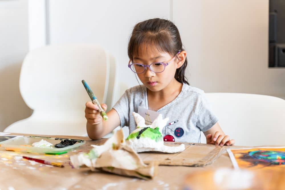 Young girl painting a clay sculpture at the Arts Umbrella.