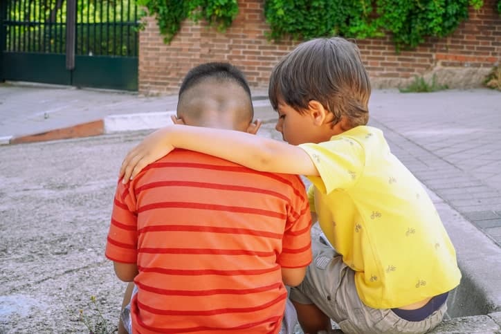 A boy with this arm over another boy to console him.