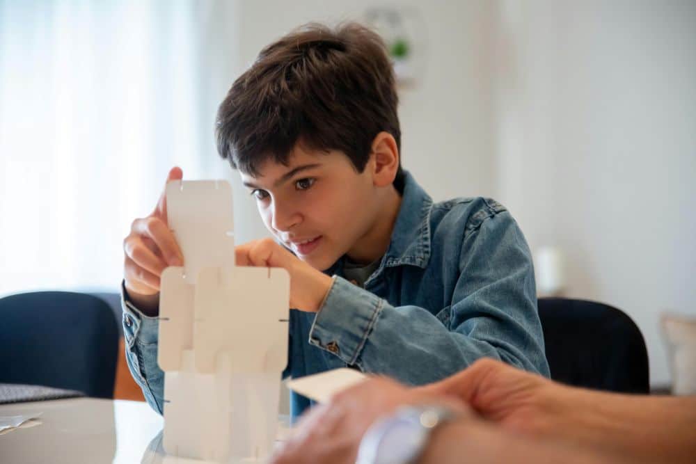 Boy solving a problem with cardboard pieces.
