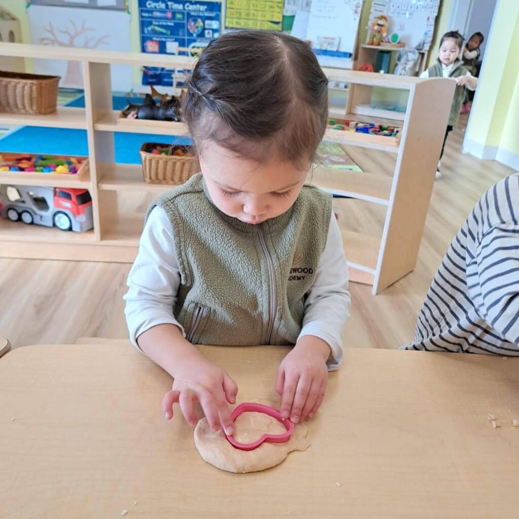 Child playing with playdough at a table in a Rothewood Academy classroom