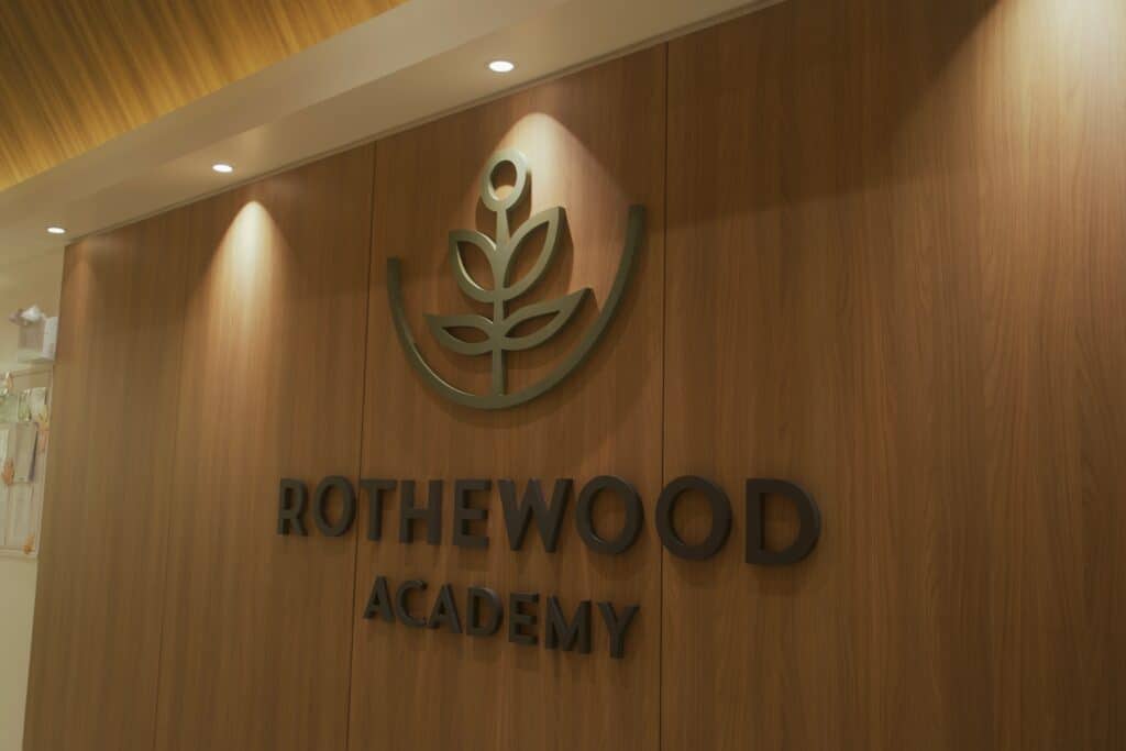 Rothewood Academy logo displayed on a wood-paneled wall